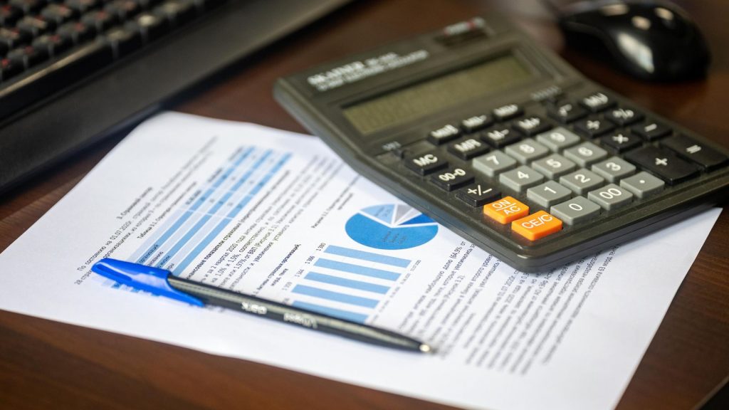 Calculatrice, stylo et rapport financier pour estimer les frais de notaire à Vincennes